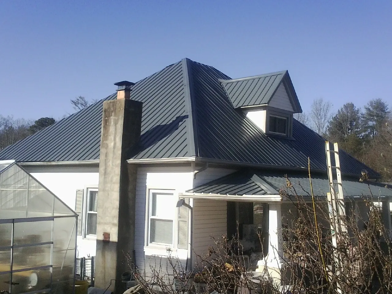 Dark blue standing seam metal roof on a white farmhouse with dormer — Slate & Tile Roof Repair by Roofing Brothers in Munroe Falls