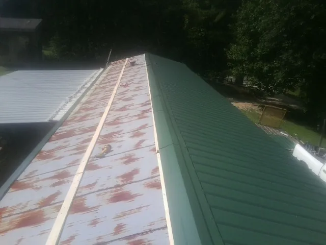 Old rusted panels beside newly installed green metal roofing — Wind Damage Roof Repair by Roofing Brothers in Munroe Falls