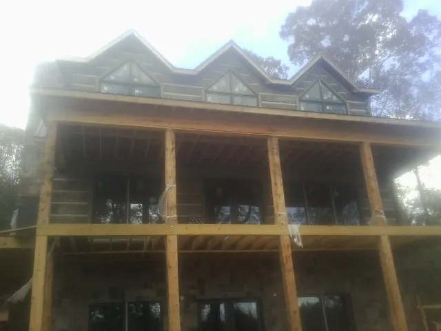 Dormers and porch framing on a large log home under construction — Roof Coating work by our crew in Munroe Falls