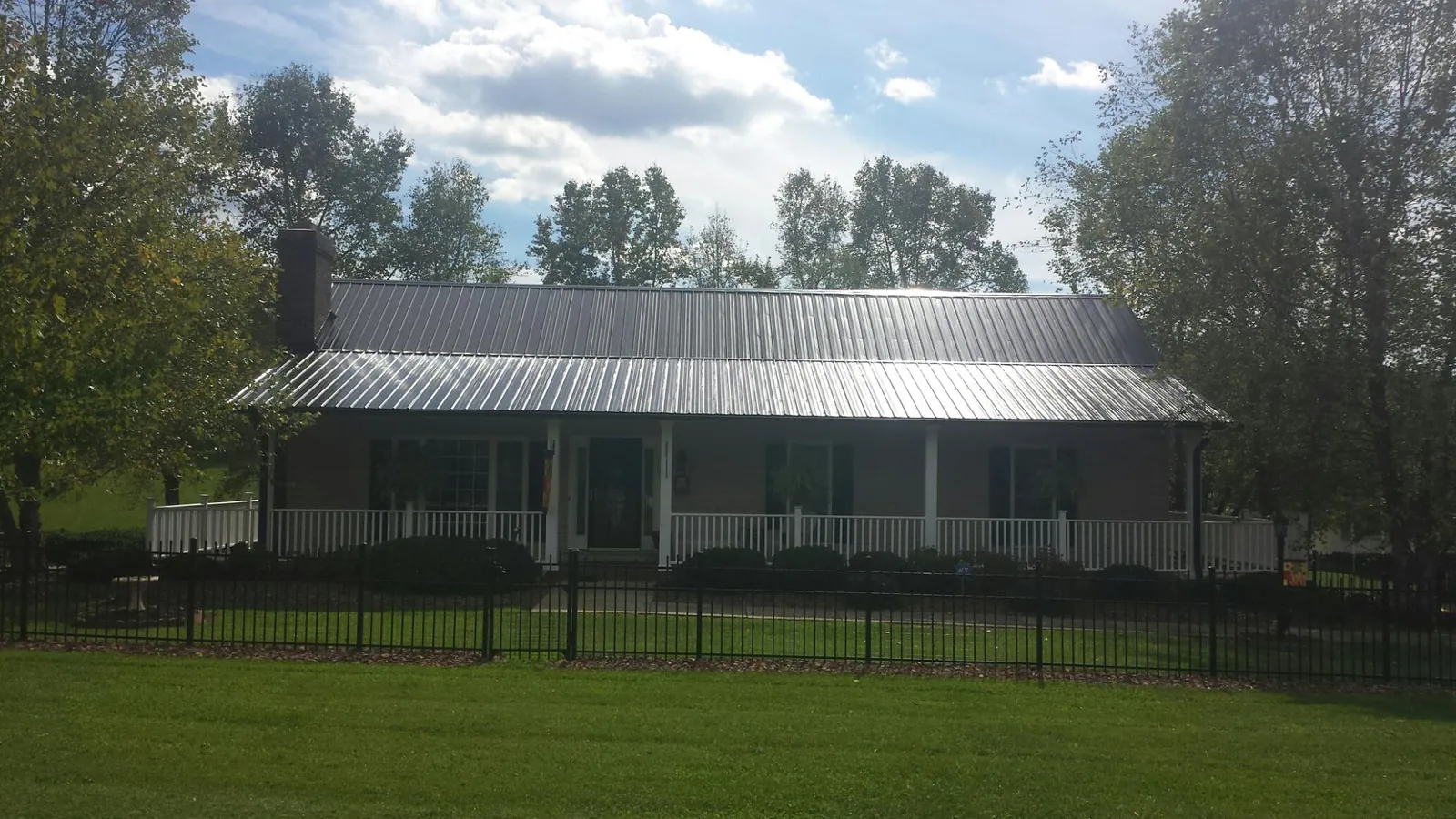 Gray metal roof on a brick ranch with a full width front porch — Gutter Guard Installation work by our crew in Munroe Falls