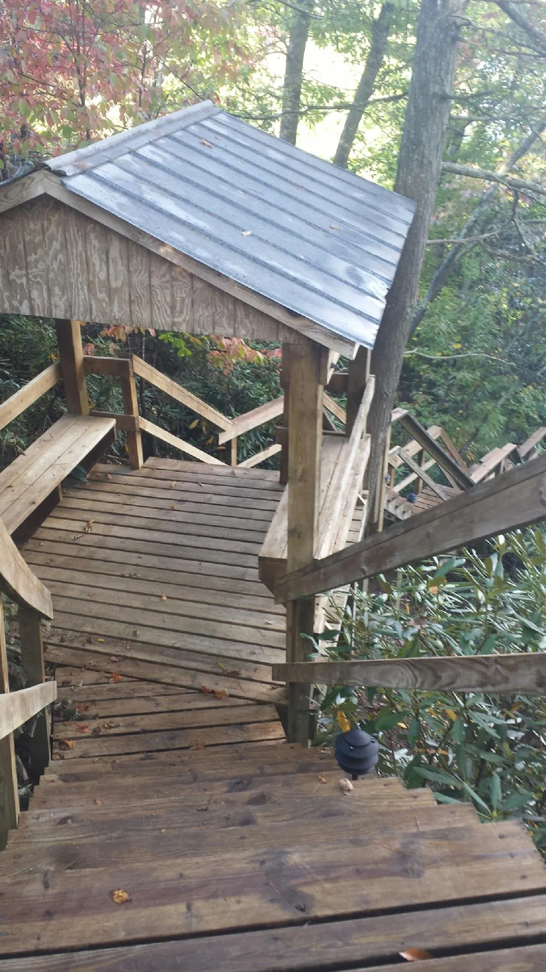 Metal roofed shelter over wooden steps on a wooded walkway — Skylight Repair & Installation work by our crew in Munroe Falls