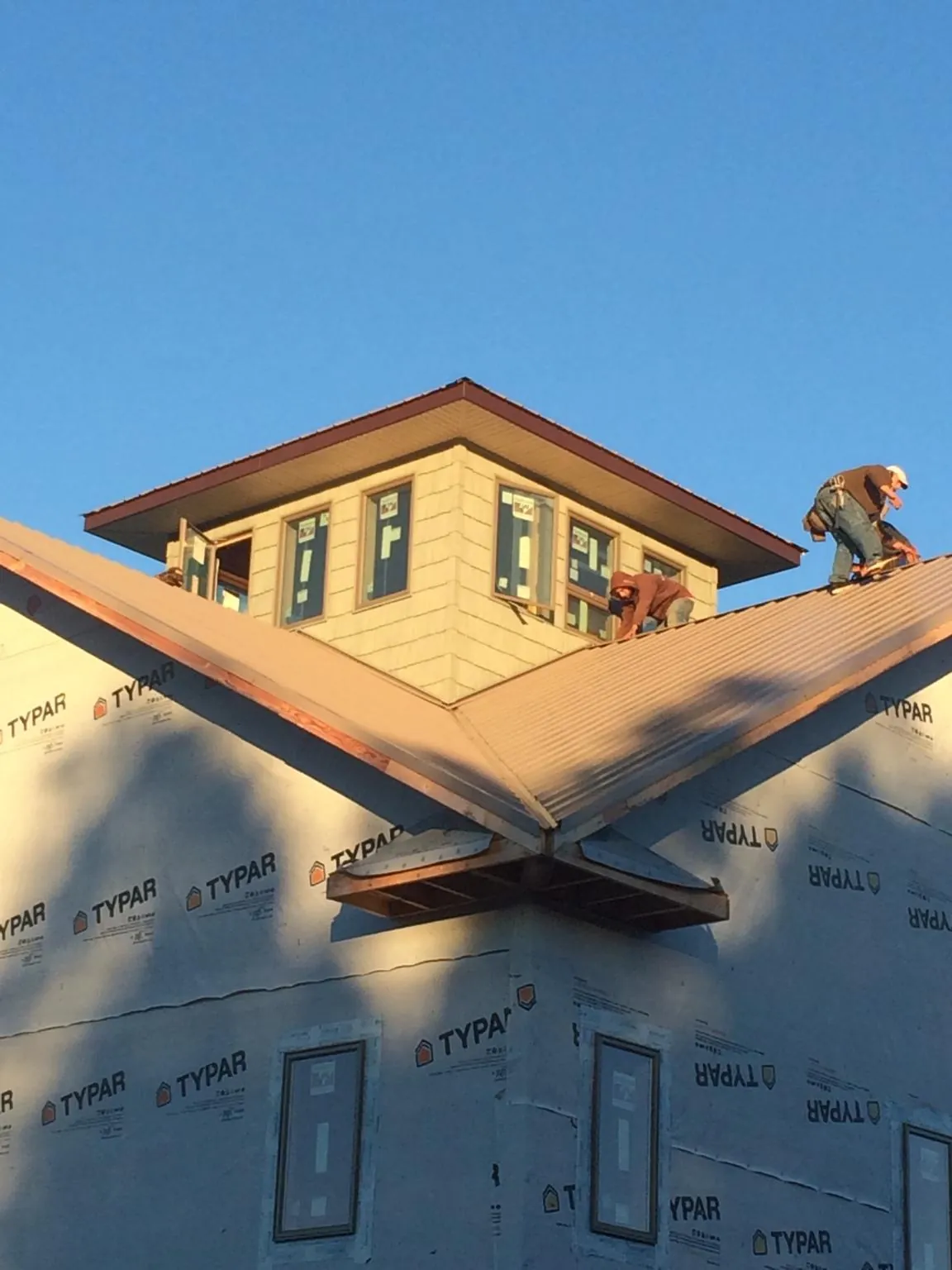 Roofers working around a rooftop cupola on a new metal roof at sunset — Roof Waterproofing in Munroe Falls by Roofing Brothers